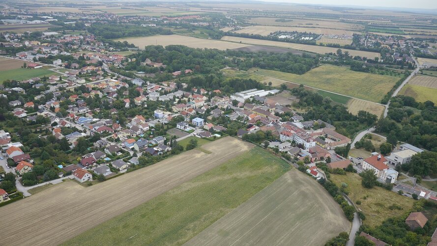 Bild einer Region von oben, auf dem Häuser im Grünen abgebildet sind.