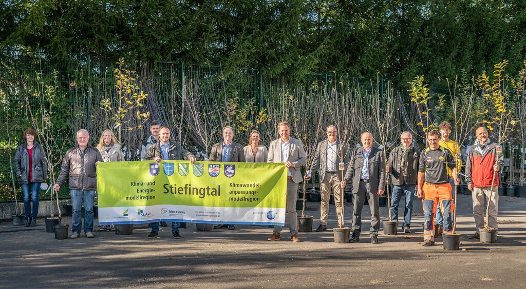 Obstbäumen und Menschen, die den Banner der KLAR! Region Stiefingtal vor sich halten