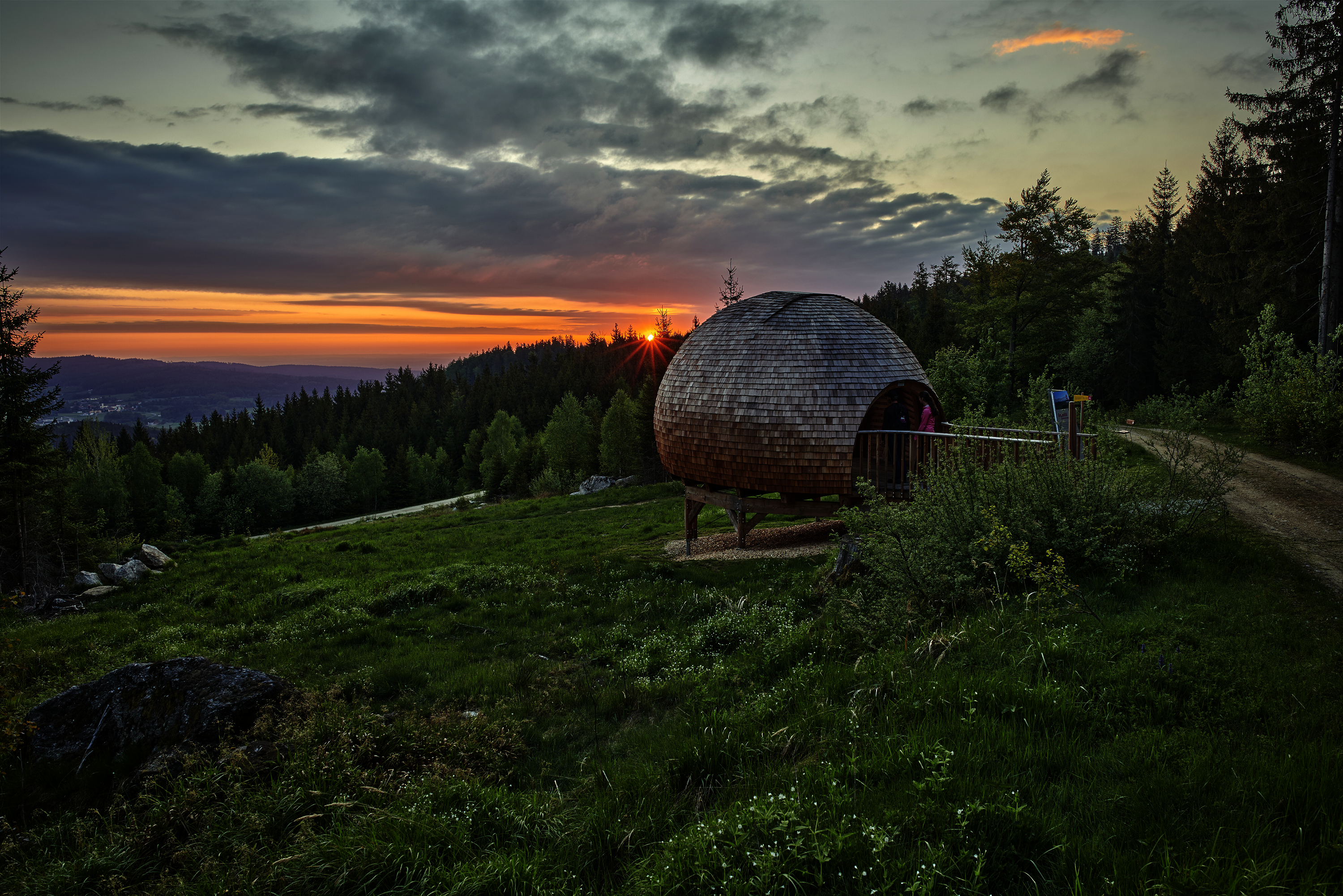 Ausblick vom Berg mit Sonnenuntergang und einer kleinen Hütte am Hang